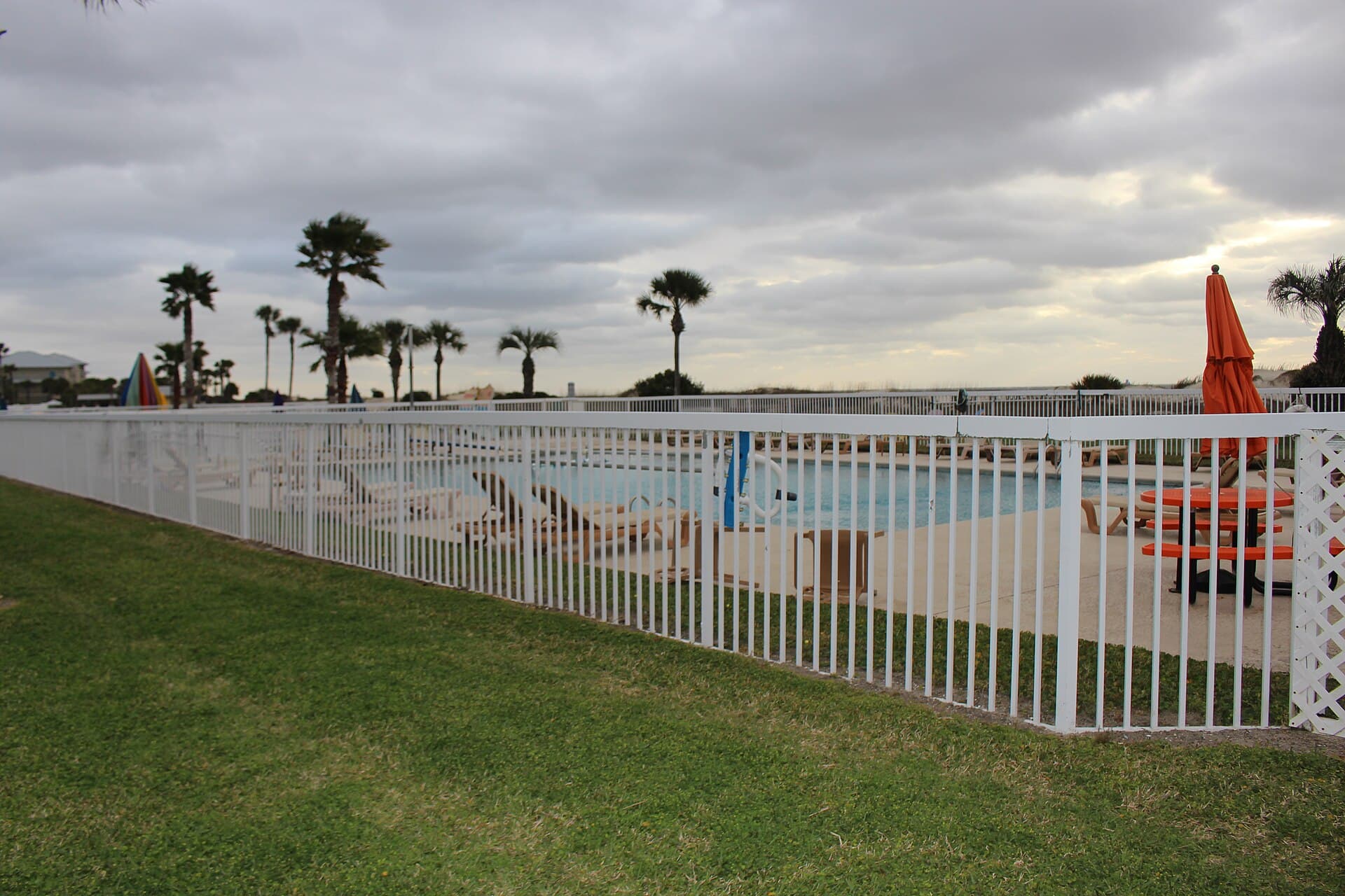 A metal swimming-pool fence beside the water, standing in for the barrier work Australian glass and aluminium pool fences are asked to do.